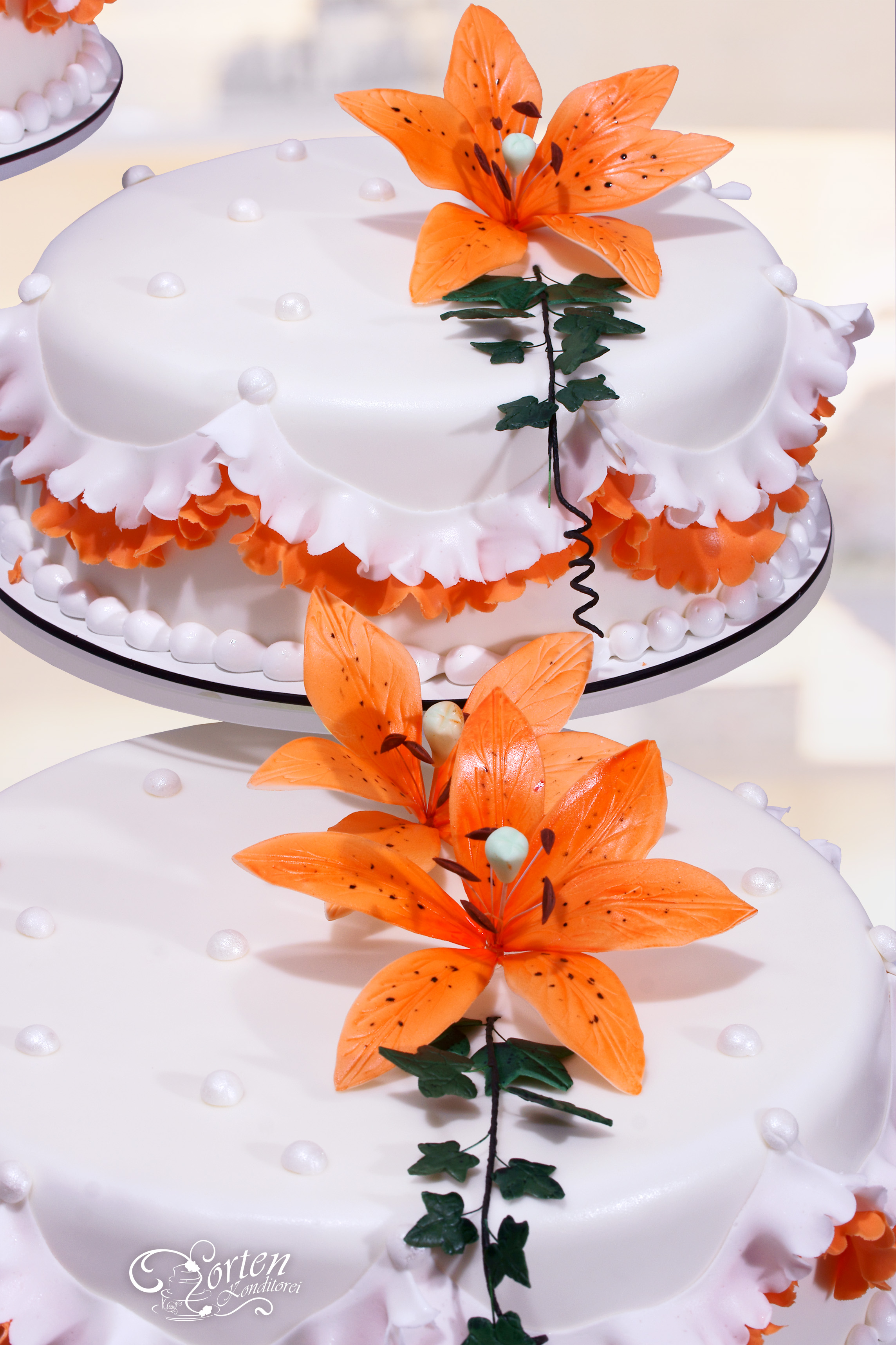 Detailansicht Hochzeitstorte mit lilien in orangenem Ton..