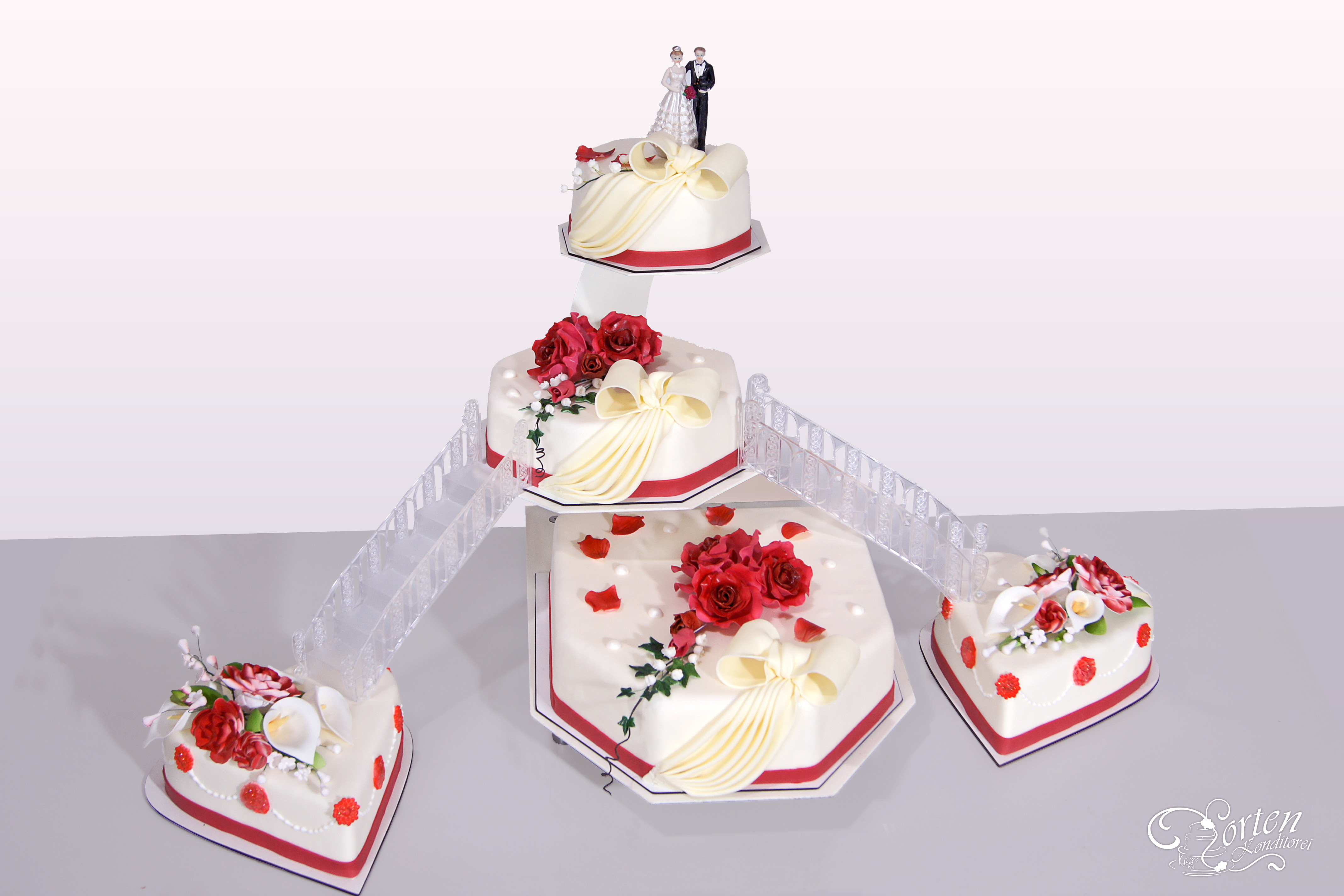 Hochzeitstorte in 8 eck-Form, rote tee-Rosen mit Efeu. Tortengrößen von ca.:  34x38, 27x27, 19x19 und 2 herzförmige Torten in ca. 24 cm, je nach Schnittgröße ca. 140 Tortenstücke.
