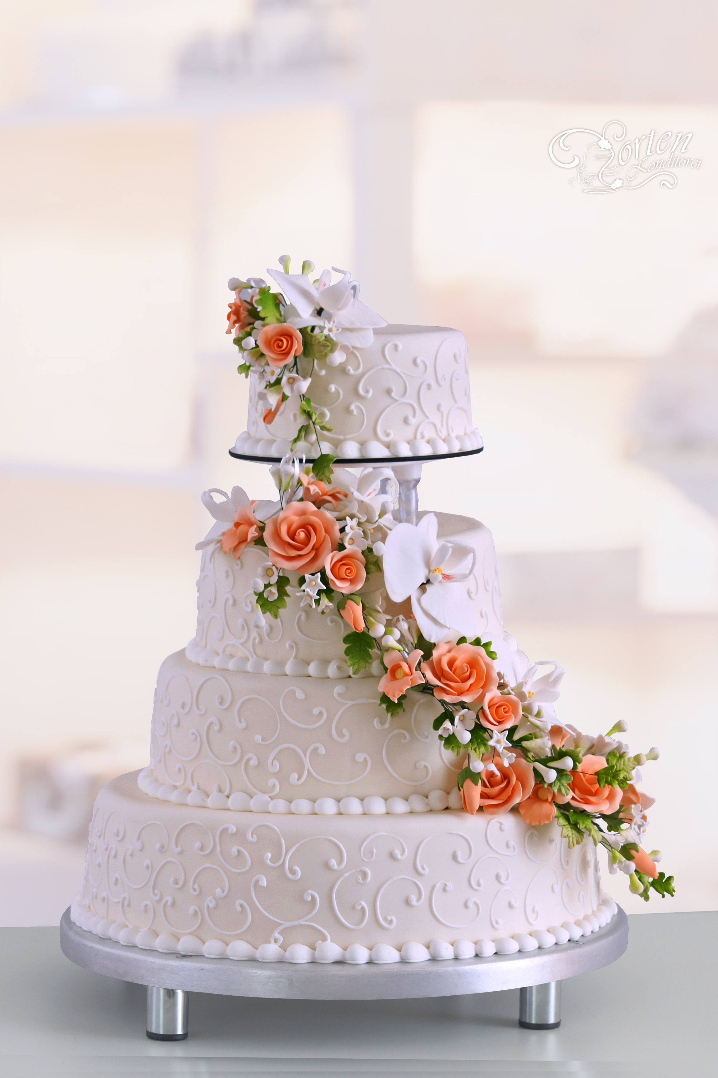 Vierstöckige Hochzeitstorte in Champagner-Ton mit aufwendiger Blumenranke in orange mit weißen-Orchideen. Die obere Torte ist getrennt, diese kann man z. B. einfrieren und später verzehren.