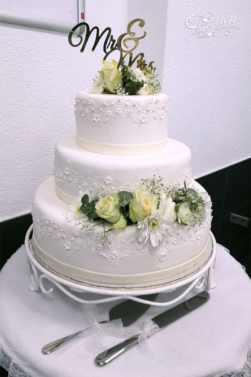 Hochzeitstorte geschmückt mit den frischen Blumen